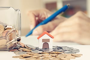Jar of Coins overflowing under house figurine